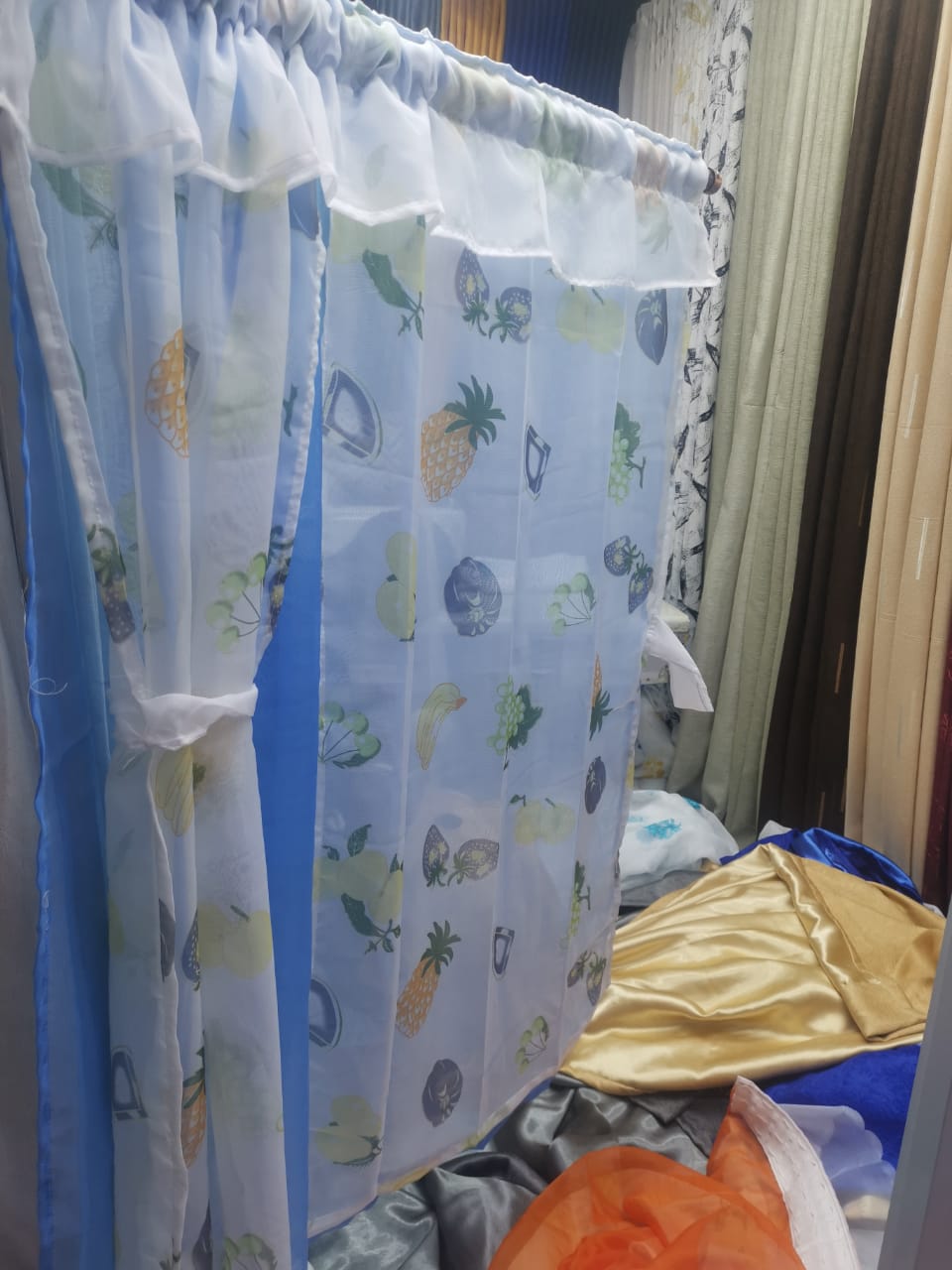 kitchen curtain. It appears to be a sheer curtain with a pineapple pattern. The curtain is tied back to let in light.