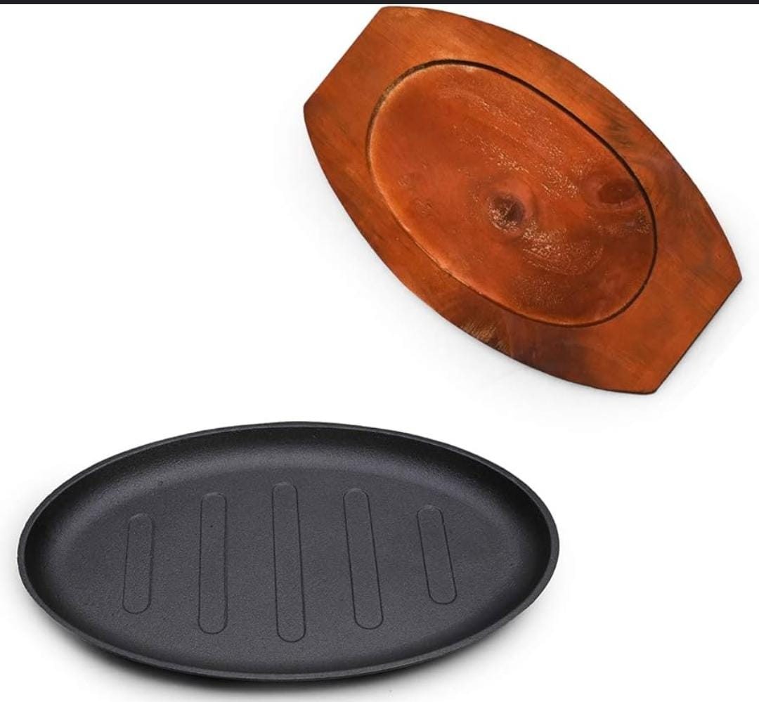 Cast iron hot sizzling plate on wooden tray