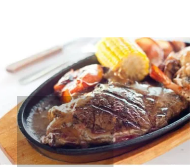 Cast iron hot sizzling plate on wooden tray
