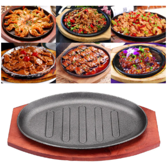 Cast iron hot sizzling plate on wooden tray