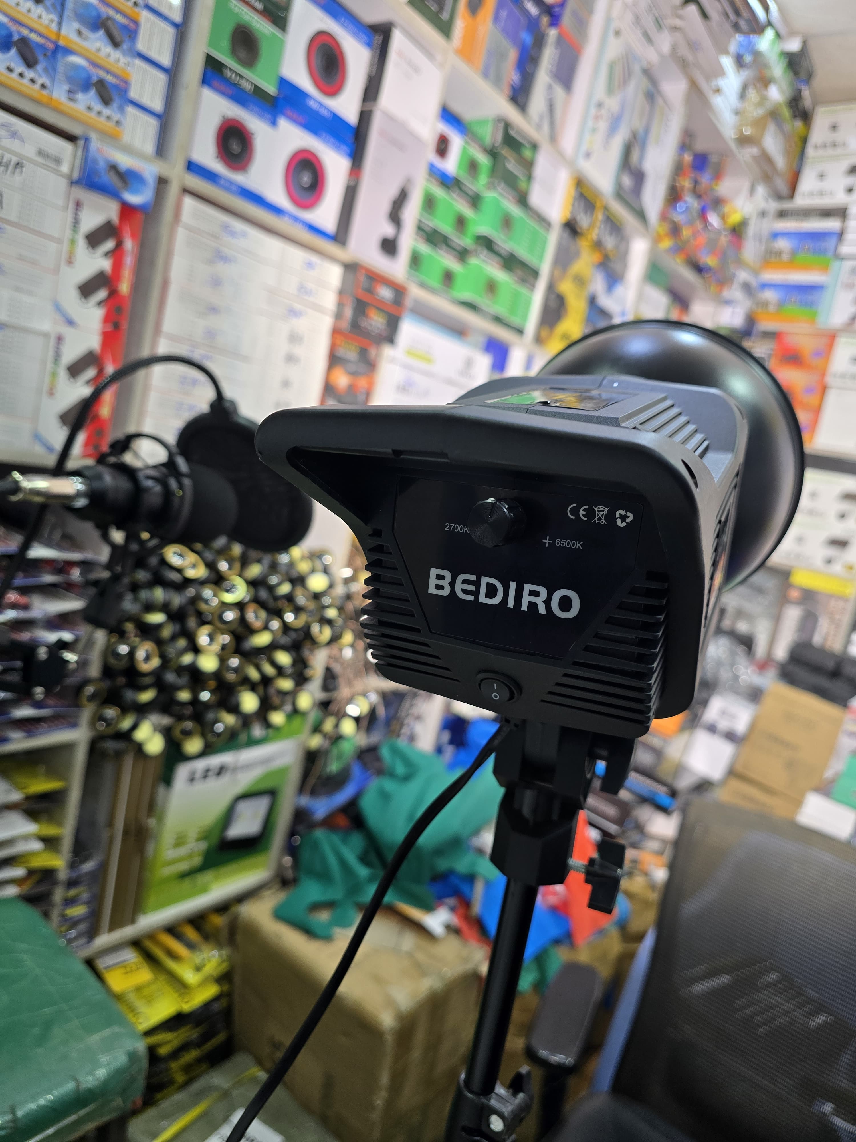 Bediro BD-400S studio light mounted on a light stand in a store. This type of continuous lighting equipment is used for photography, filming, and live streaming. 
The lamp has a power capacity of 100W