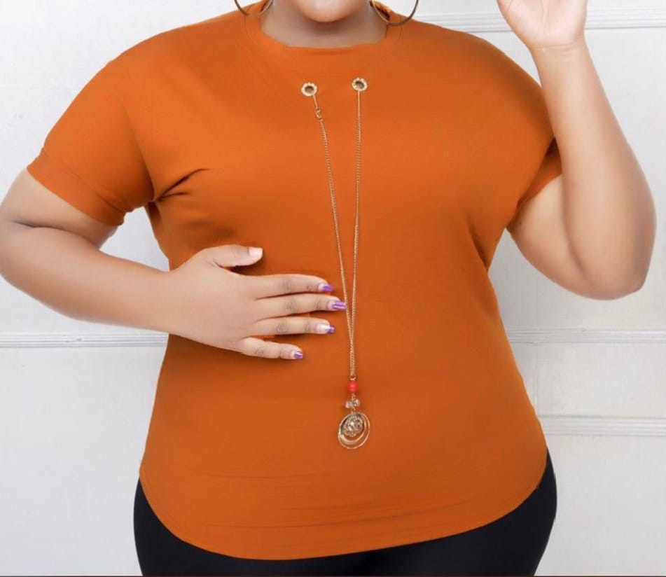 Women Essential Luxe Classic Tee with a long gold-tone necklace with a red bead and circular pendant. Size: Free size