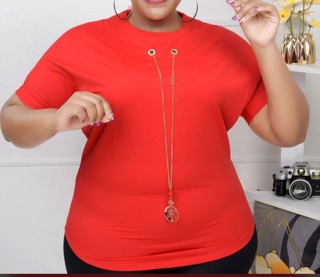 Women Essential Luxe Classic Tee with a long gold-tone necklace with a red bead and circular pendant. Size: Free size