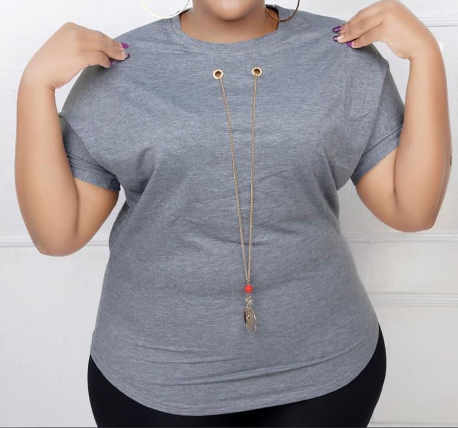 Women Essential Luxe Classic Tee with a long gold-tone necklace with a red bead and circular pendant. Size: Free size
