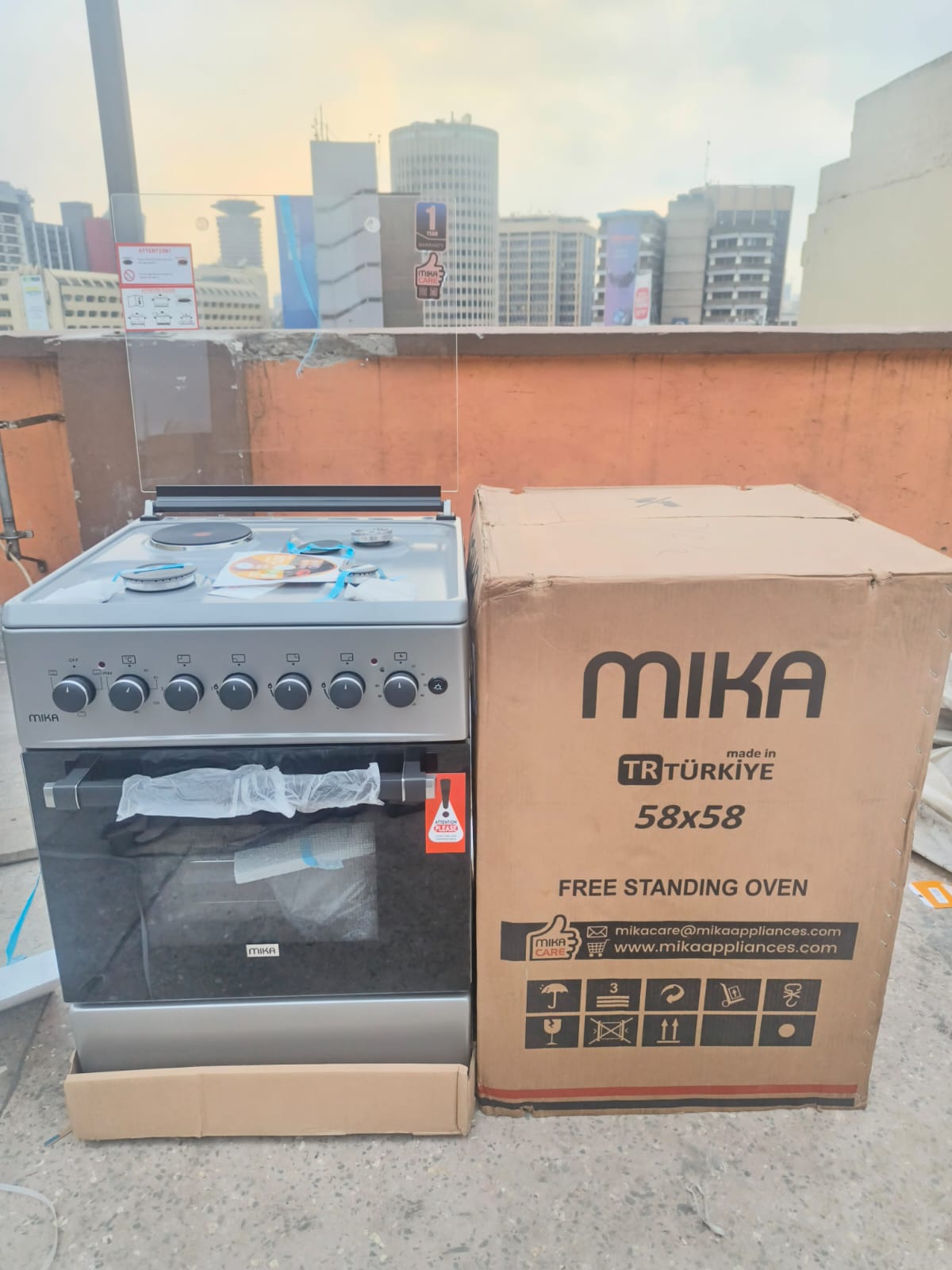 Silver Mika Standing Cooker 58 x 58 3 Gas + 1Electric Hotplate with Electric Oven, Wide enamel coated pan support,Heavy Duty Matt Finish Burner Caps,One Hand Integrated Auto-ignition,Mechanical timer