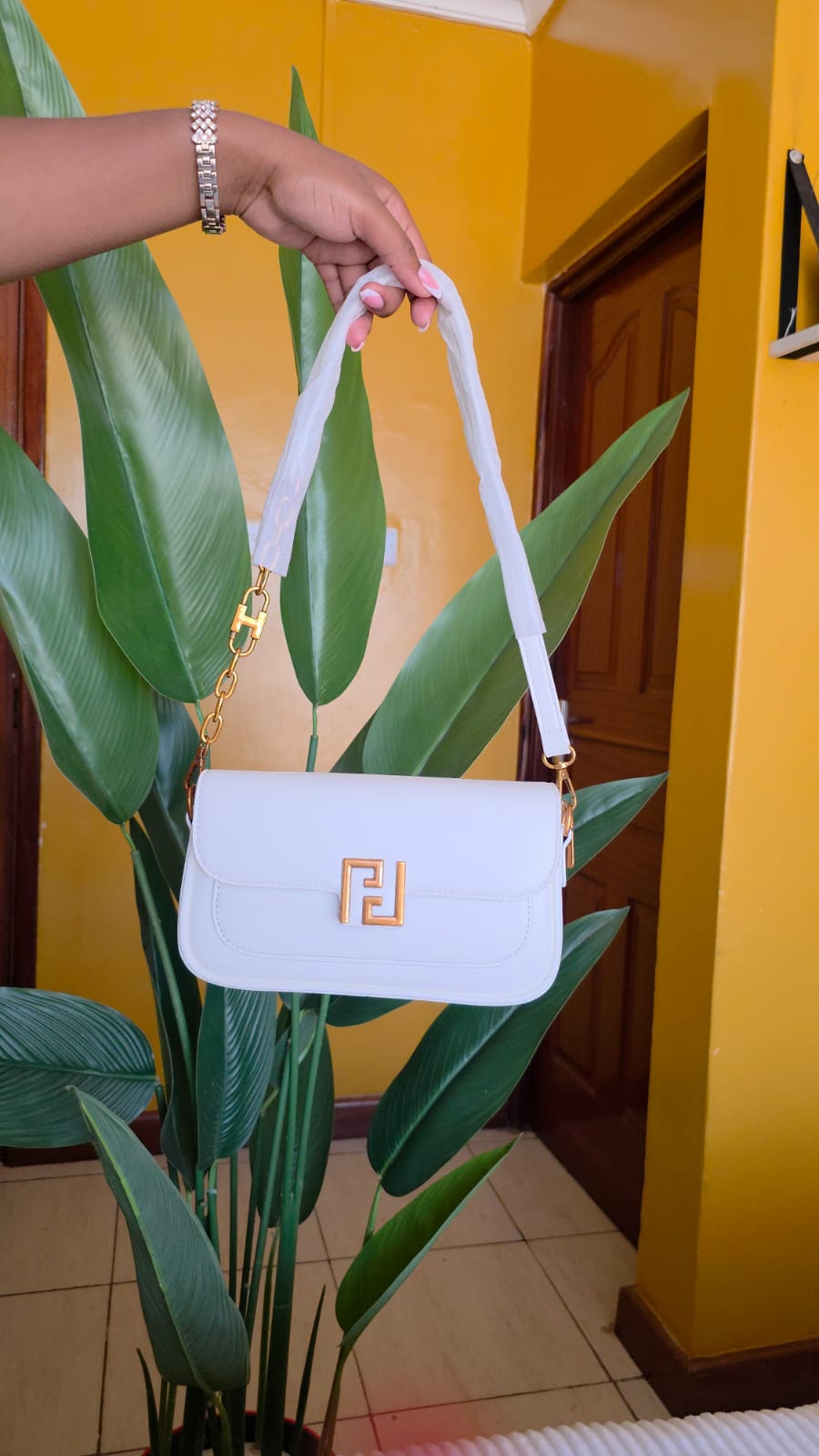 This is a sleek, minimal luxury shoulder bag in a soft,white tone. It features a structured rectangular silhouette with clean edges and a smooth finish that gives it a refined, polished look.