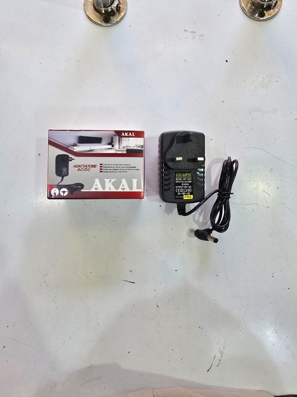 AKAL AC/DC power adapter. 
Input: 100-240V AC, 50/60Hz
Output: 12V DC, 2A
Plug Type: UK 3-pin
Connector Size: 5.5mm x 2.1mm DC barrel plug
Common Uses: LED strips, routers, CCTV cameras, and other 12V