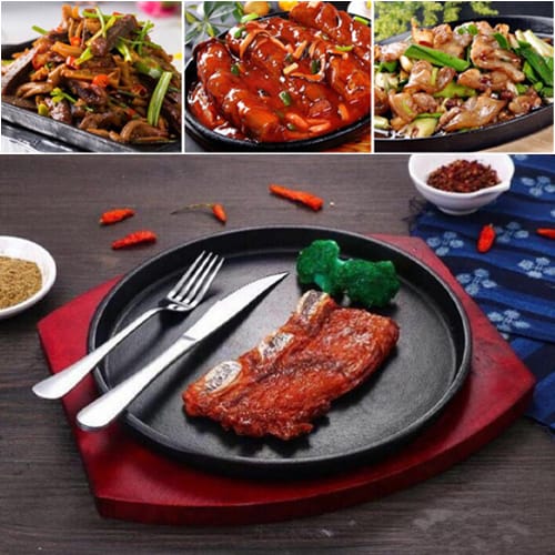 Cast iron hot sizzling pan on wooden plate