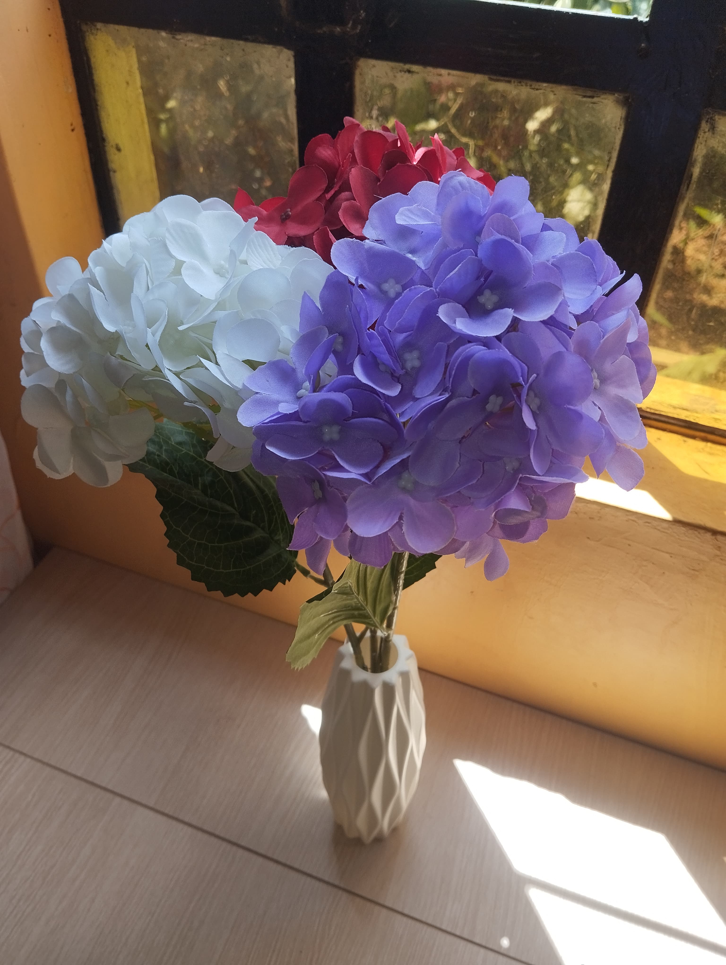 Artificial hydrangea flower  with two leaves (set of three flower stems with two leaves of different colors) in a plastic nordic vase