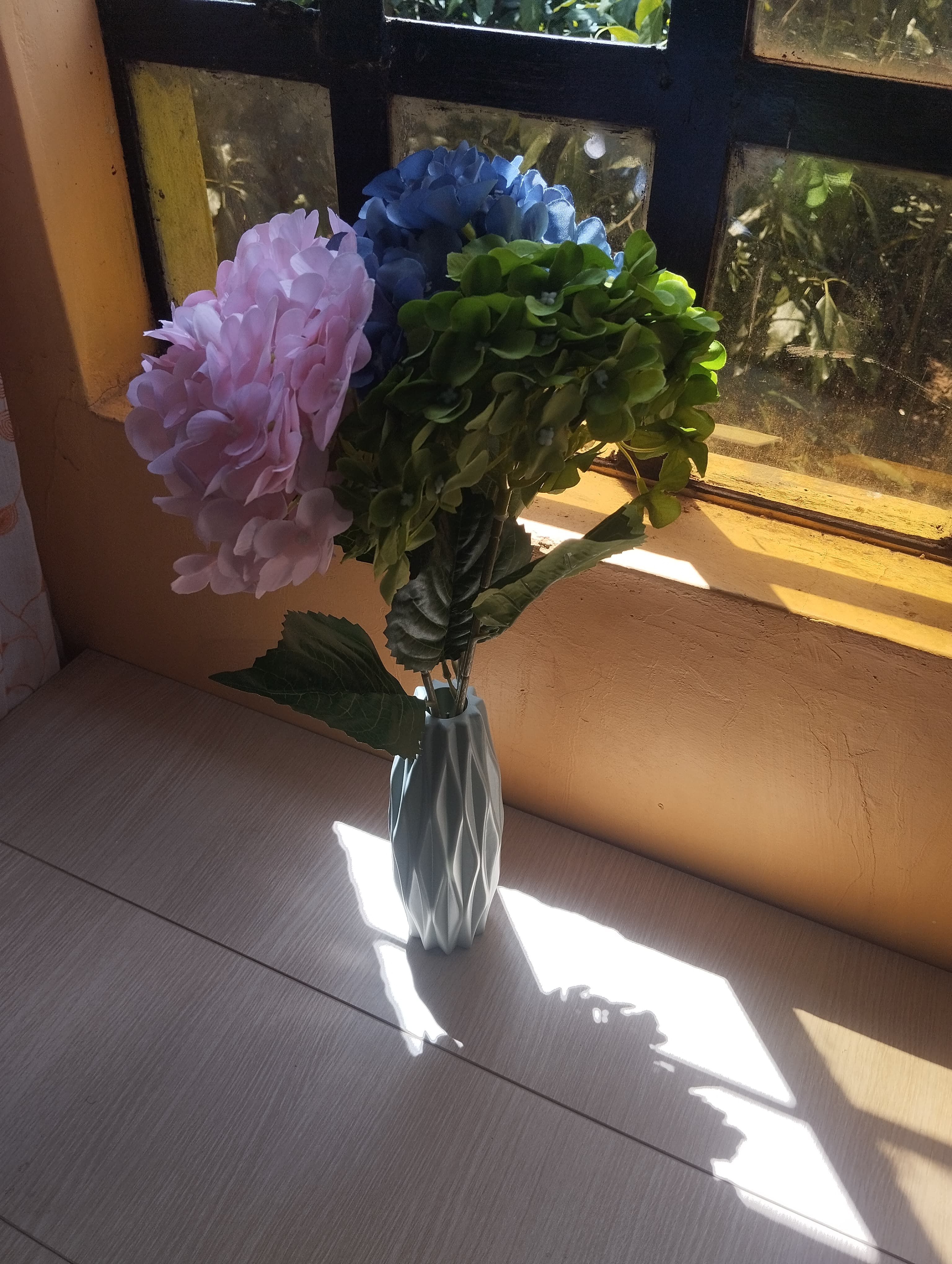 Artificial hydrangea flower  with two leaves (set of three flower stems with two leaves of different colors) in a plastic nordic vase