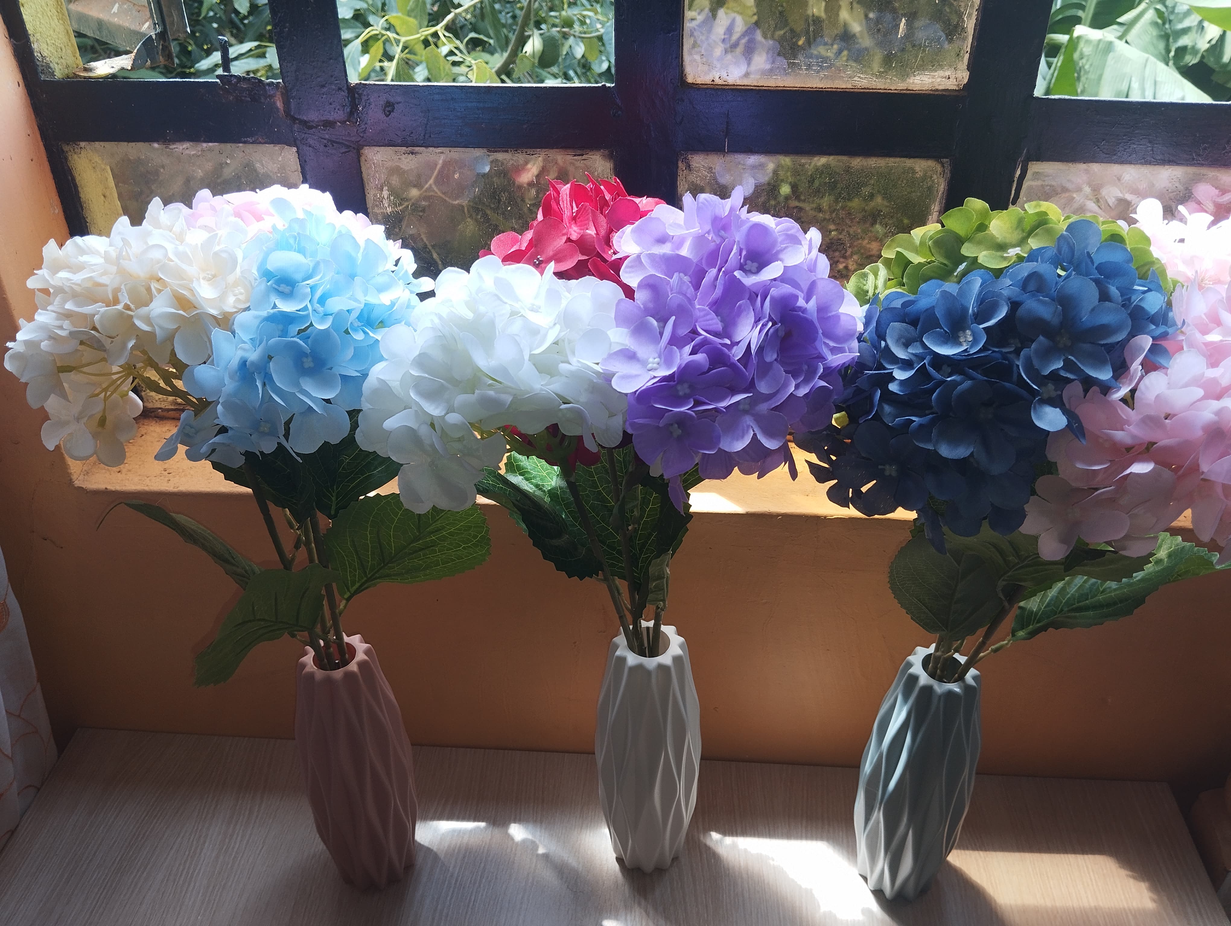 Artificial hydrangea flower  with two leaves (set of three flower stems with two leaves of different colors) in a plastic nordic vase