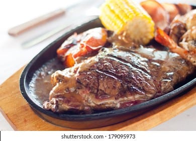 Cast iron hot sizzling plate on wooden tray - available in round and oval shape