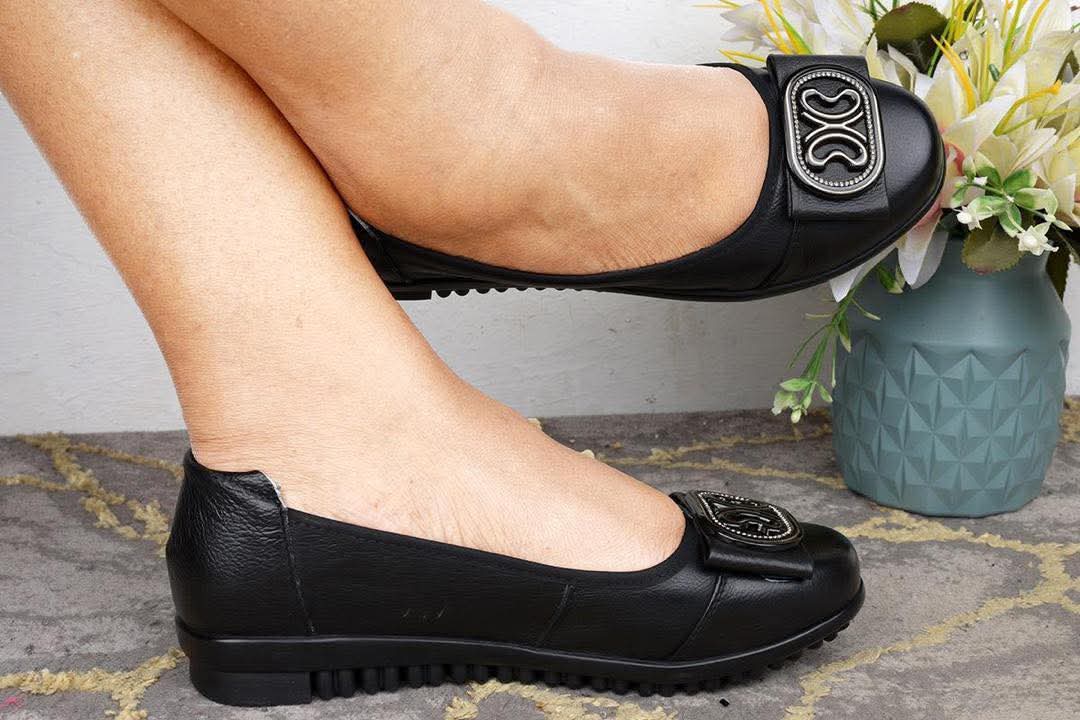 Fashionable black textured leather slip-on ballet flats With  decorative buckle detail and a ridged rubber outsole.