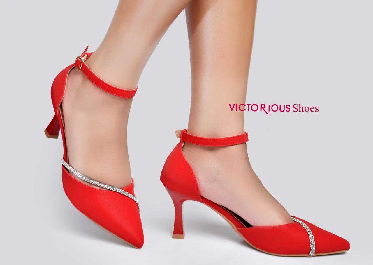 Elegant black pointed-toe kitten heels by Victorious Shoes. They feature a chic ankle strap with a delicate buckle, a subtle cut out, and a stunning curved rhinestone accent across the toe.