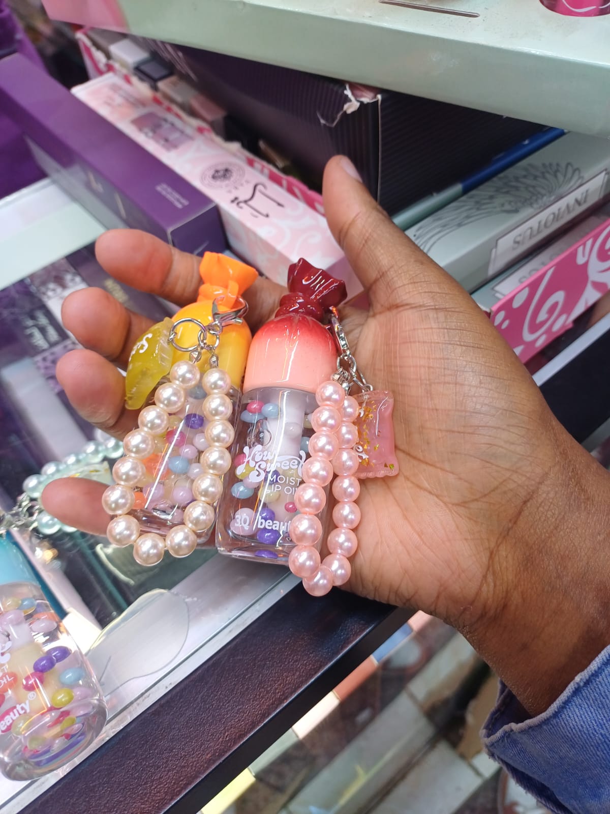 Candy-shaped mini lip oil attached to elegant pearl-beaded wristlet keychains.