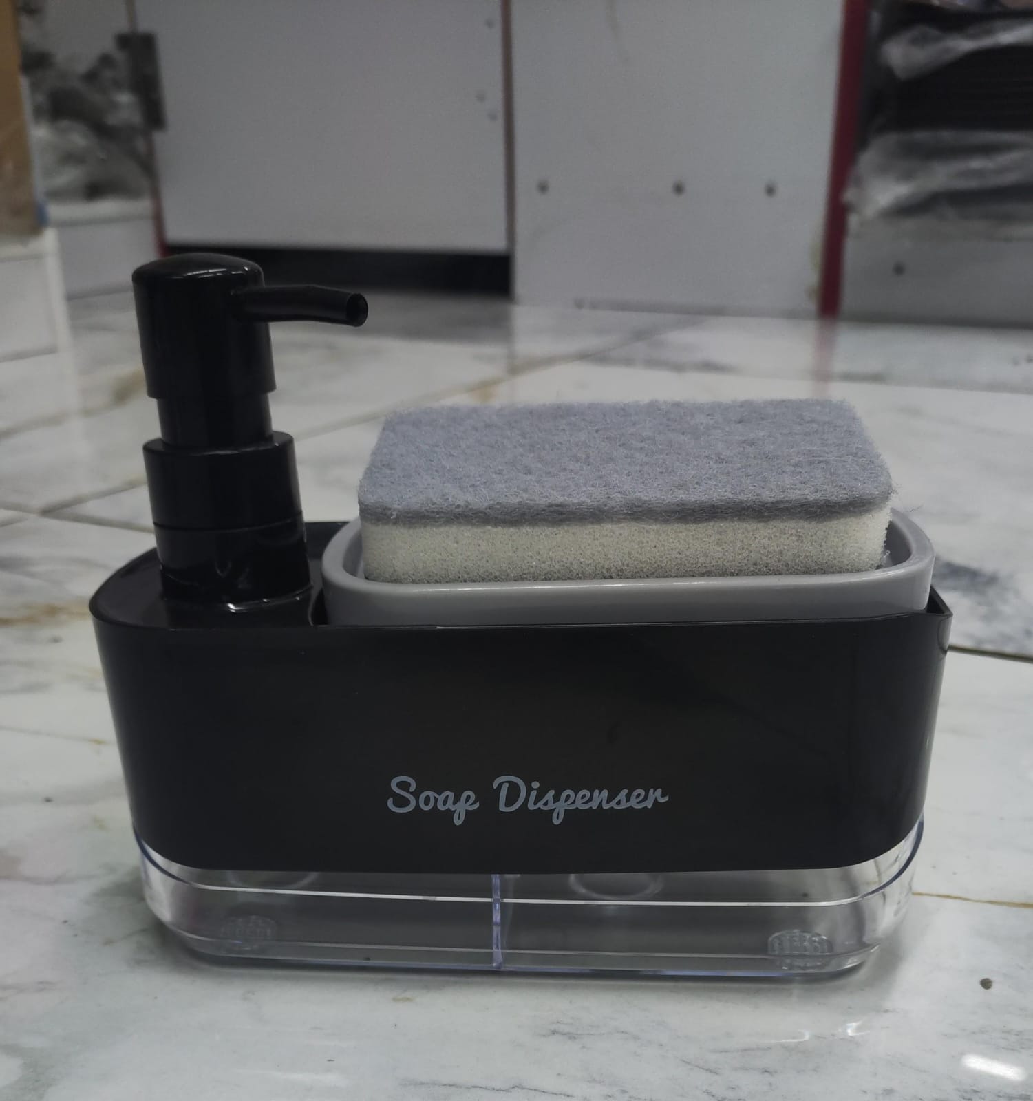 Black plastic 2-in-1 countertop soap dispenser and sponge caddy featuring a manual pump and a built-in tray holding a cleaning sponge