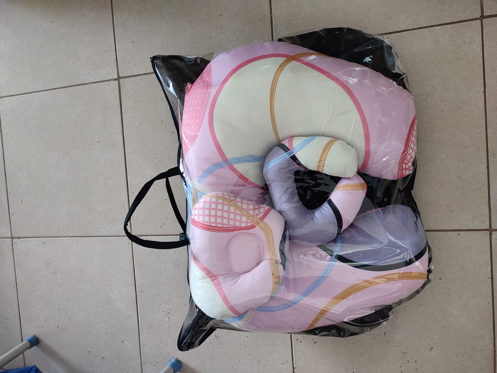 multi-functional baby nursing and feeding pillow set, tightly packed inside a clear plastic protective travel bag with a black zipper trim and handles.Ergonomic Baby Nursing Pillow  Lounger with cover