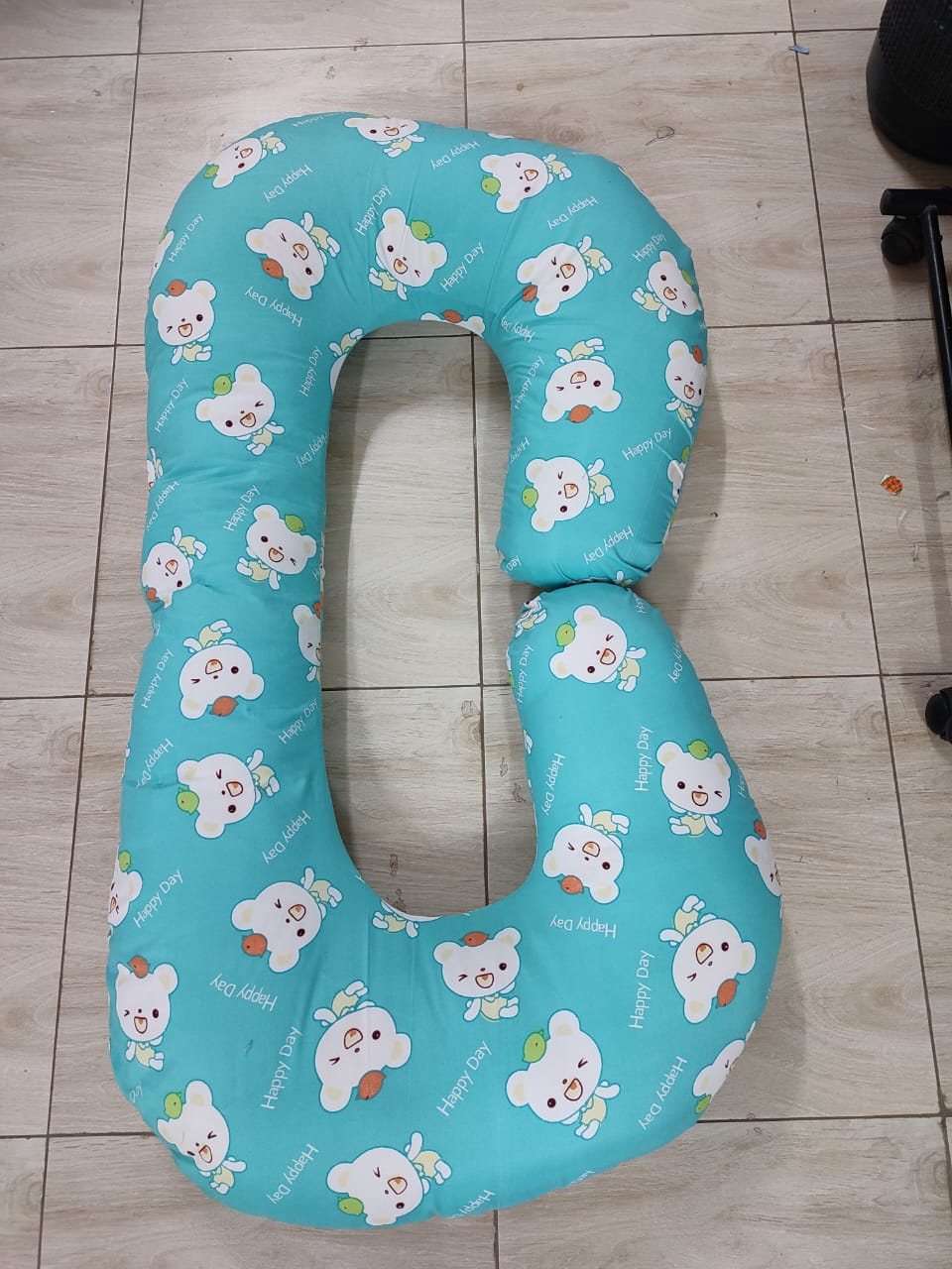 G-shaped maternity and pregnancy support pillow support pillow resting vertically on a light-colored tiled floor.Key Visual Details:Shape: It features