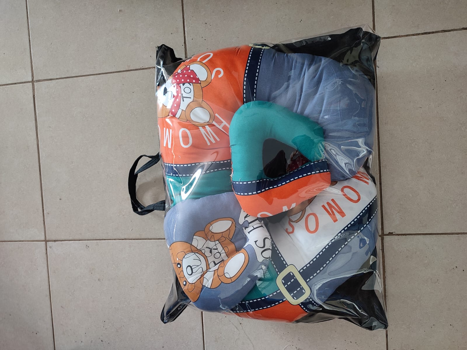 multi-functional baby nursing and feeding pillow set, tightly packed inside a clear plastic protective travel bag with a black zipper trim and handles.Ergonomic Baby Nursing Pillow  Lounger with cover