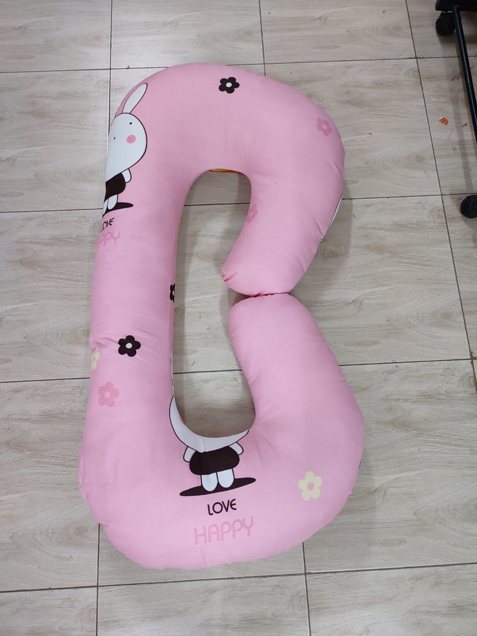 G-shaped maternity and pregnancy support pillow support pillow resting vertically on a light-colored tiled floor.Key Visual Details:Shape: It features