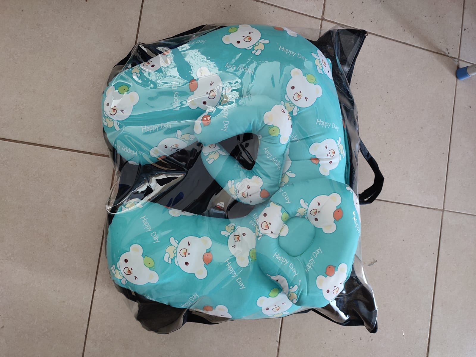 multi-functional baby nursing and feeding pillow set, tightly packed inside a clear plastic protective travel bag with a black zipper trim and handles.Ergonomic Baby Nursing Pillow  Lounger with cover